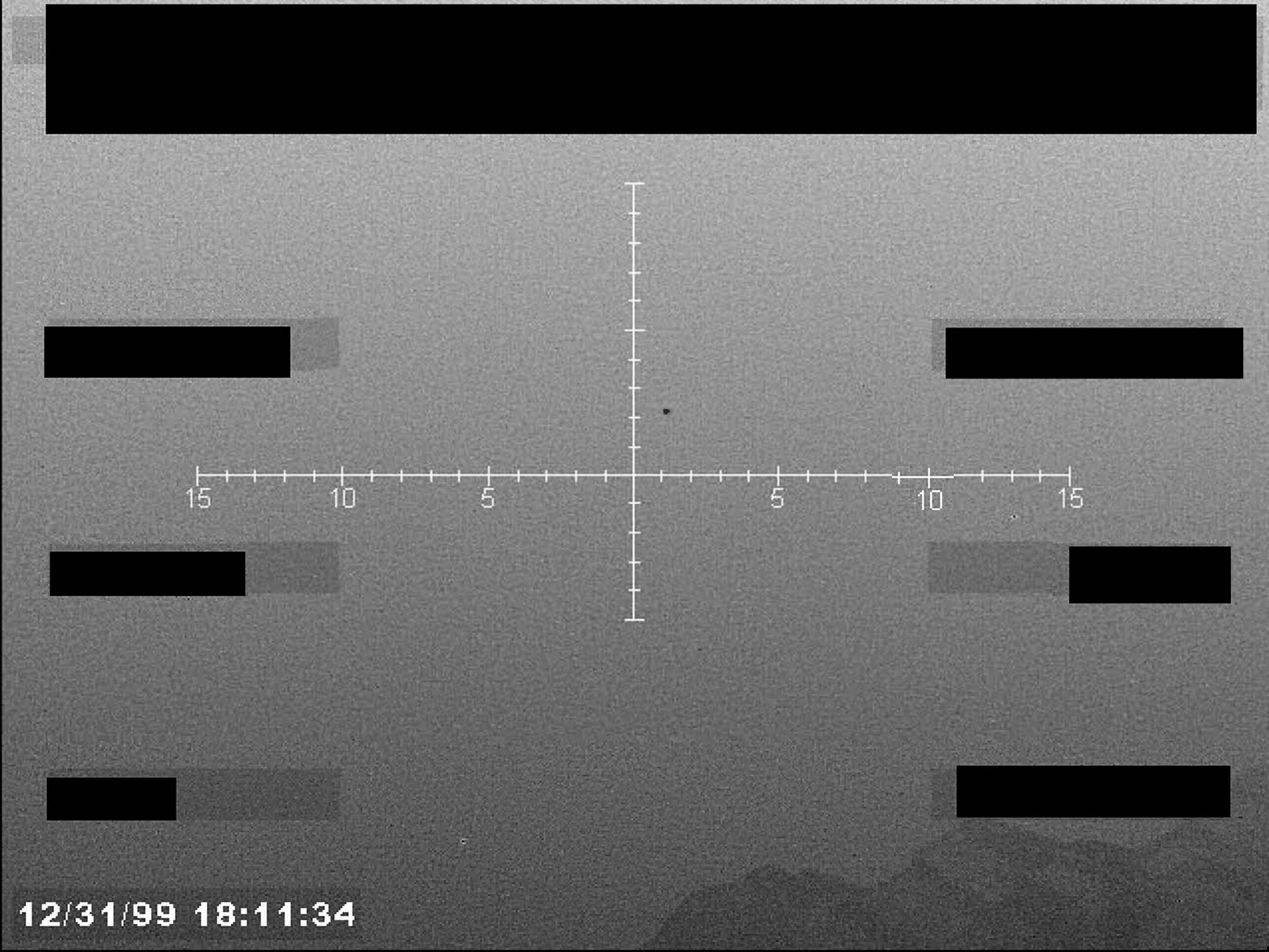 A grainy, black-and-white sensor image showing a central crosshair reticle with a small object near the center, a timestamp, and several redacted data blocks.