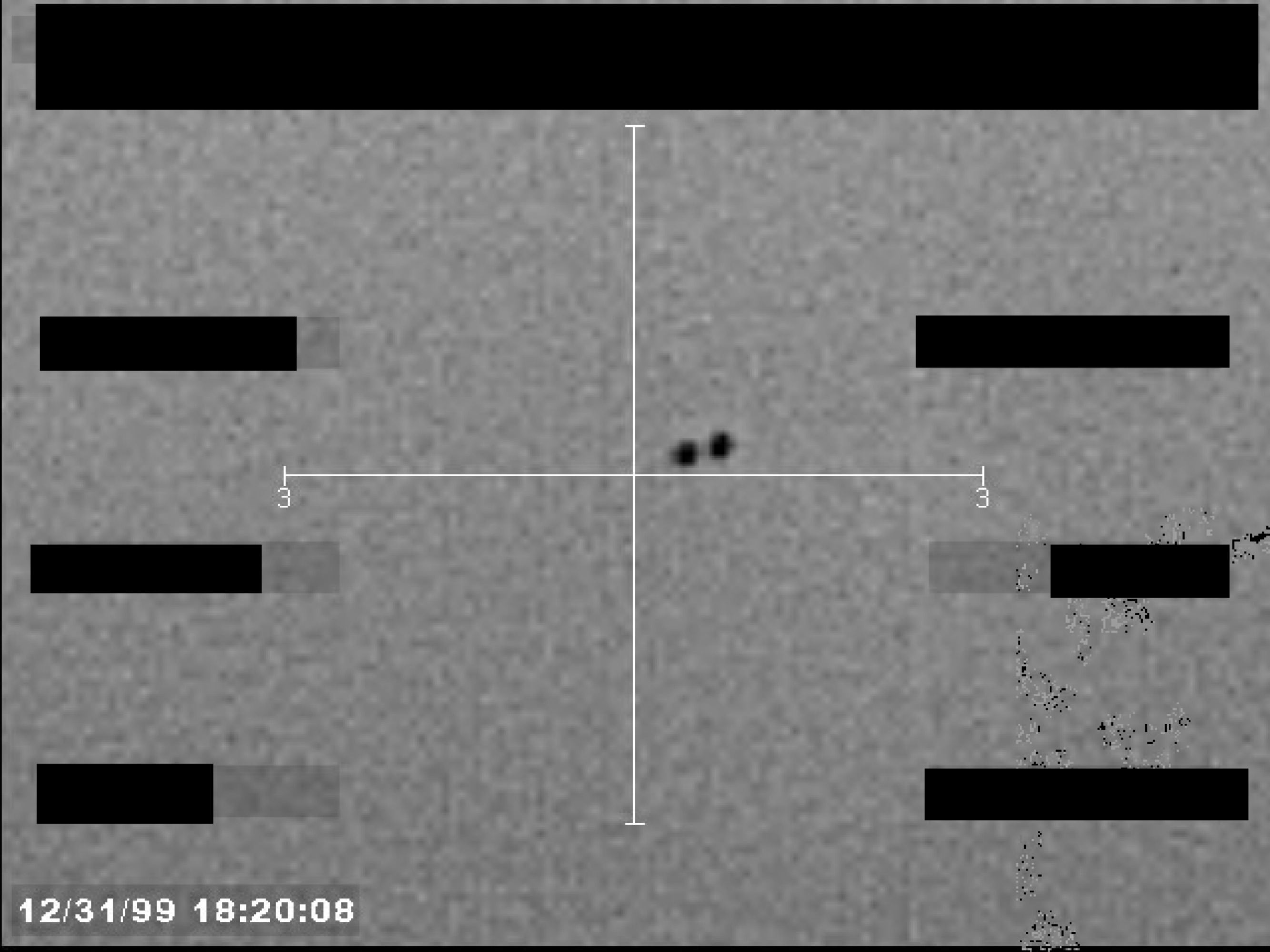 Sensor footage frame showing a crosshair targeting two small, dark objects. Several data fields are redacted.