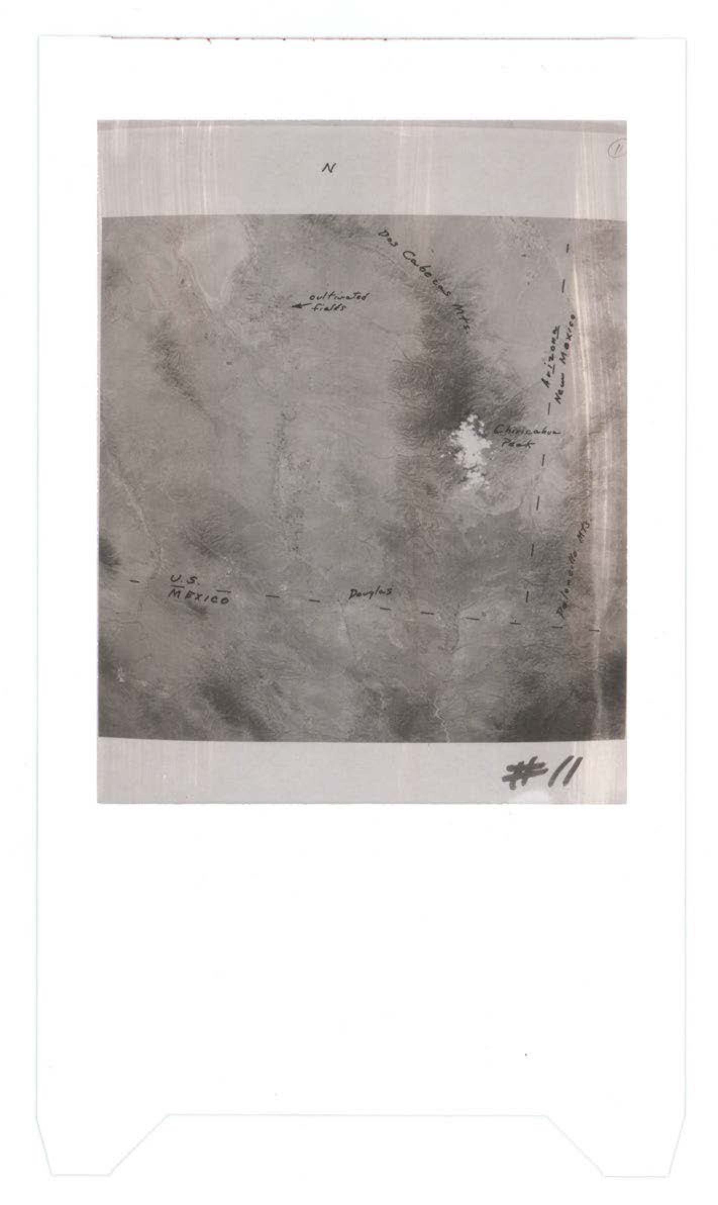 Aerial photograph showing terrain with handwritten annotations including directional marker N, continental trader, U.S. RESTRICTED, Douglas, and numbered #11