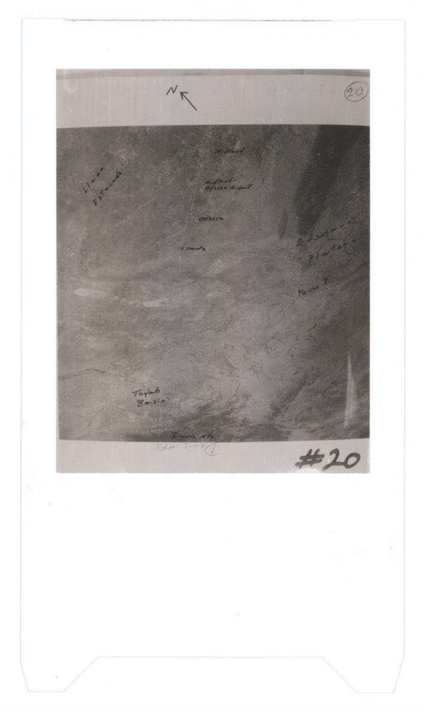 Aerial or satellite photograph with handwritten annotations indicating directional markers and geographic features including ocean