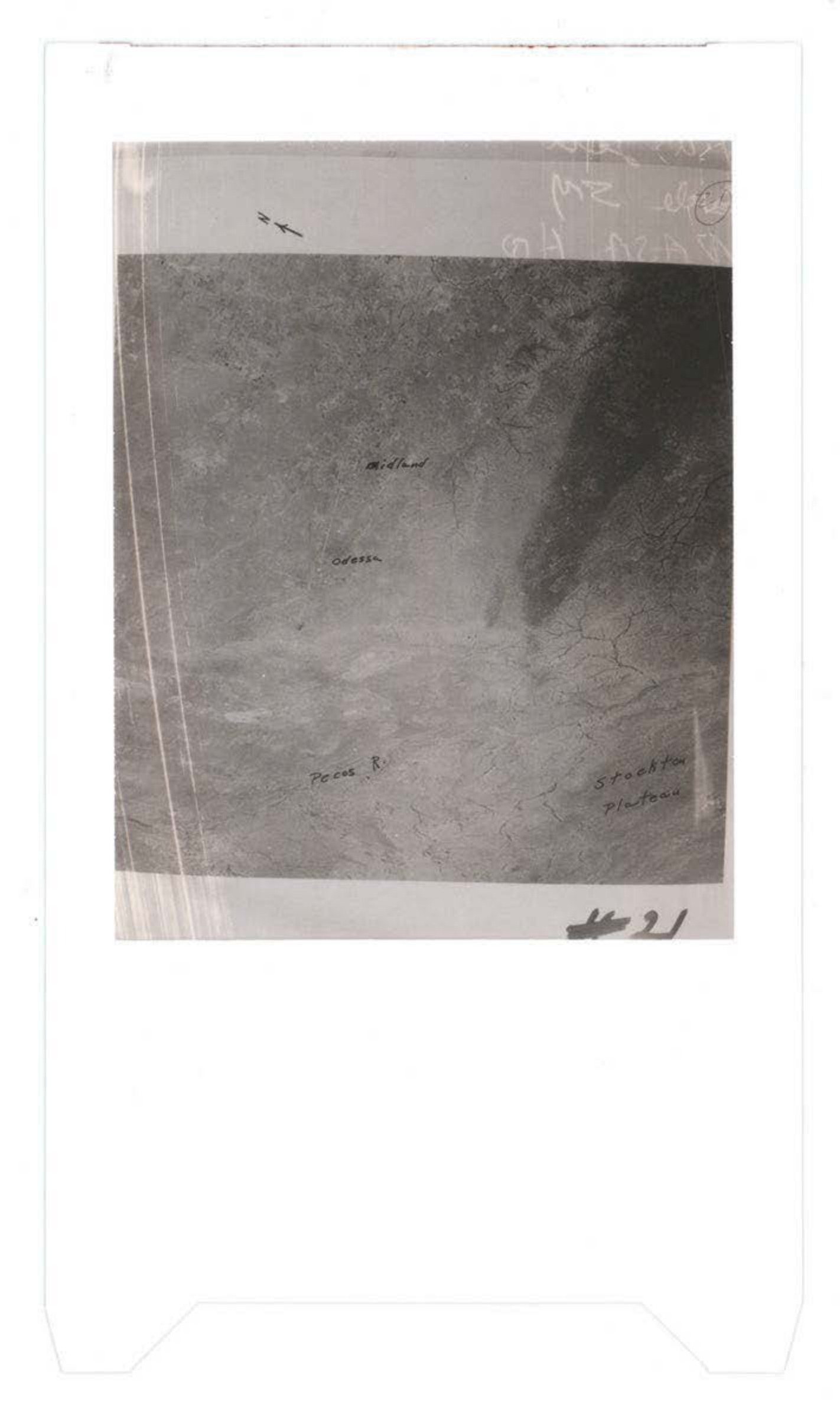 Aerial photograph showing terrain or ocean surface with aircraft silhouettes visible in upper portion and handwritten annotations