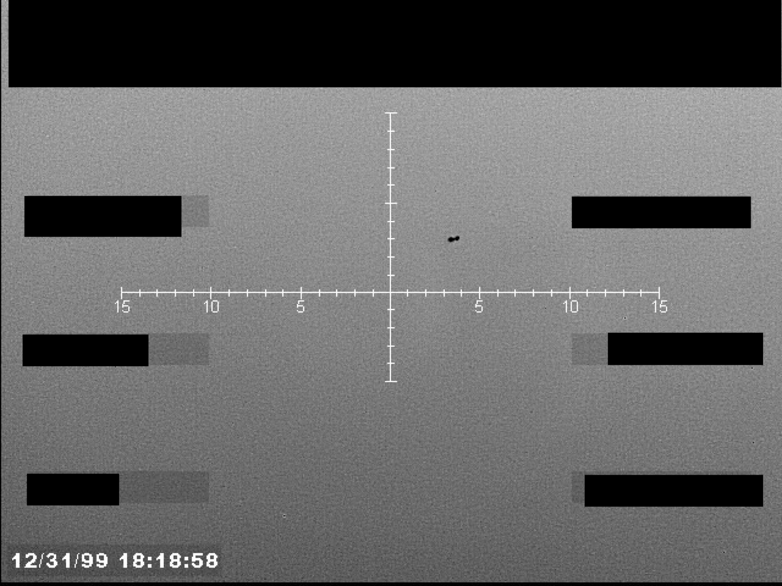 Sensor display showing a central crosshair reticle with numerical markings and an unidentified object near the center.
